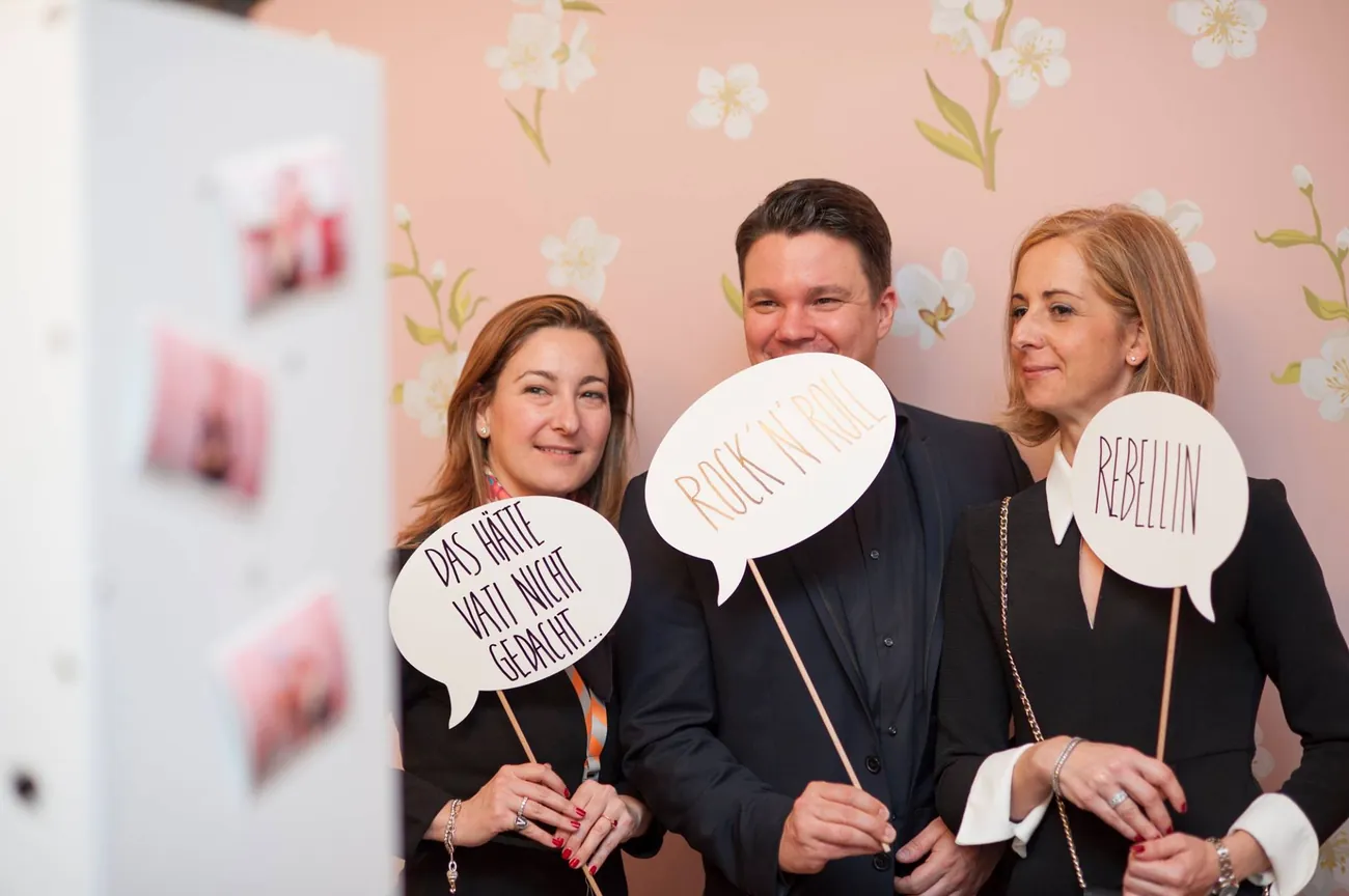 Gäste posieren mit Foto-Props vor der SNAPSHOT2GO Fotobox auf einem Premium-Event